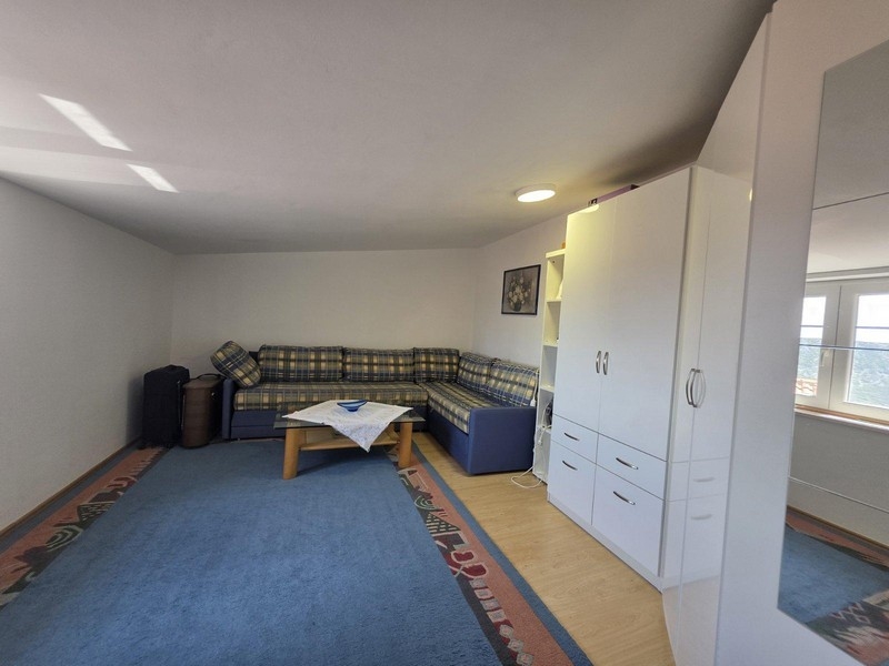 Séjour avec canapé d'angle, tapis et placard