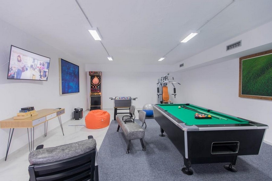 Salle de loisirs et de jeux avec table de billard et espace fitness