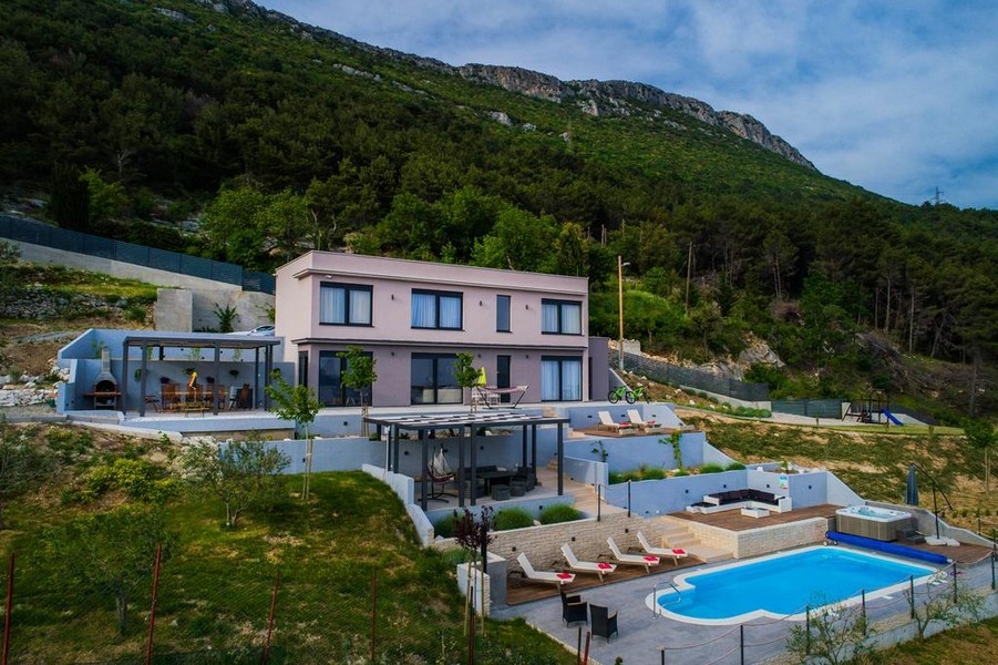 Maison rose avec piscine et jacuzzi devant la montagne