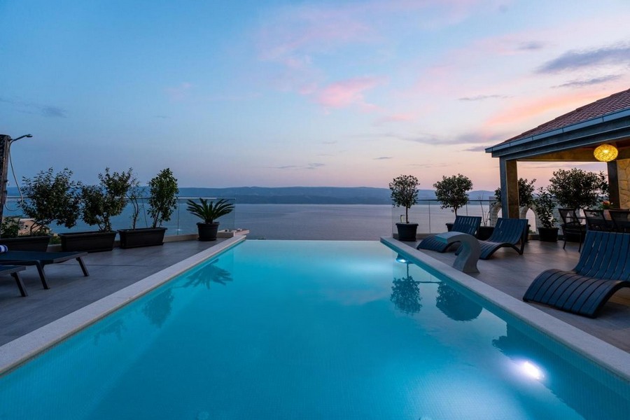 Piscine au coucher du soleil avec bacs à plantes et transats