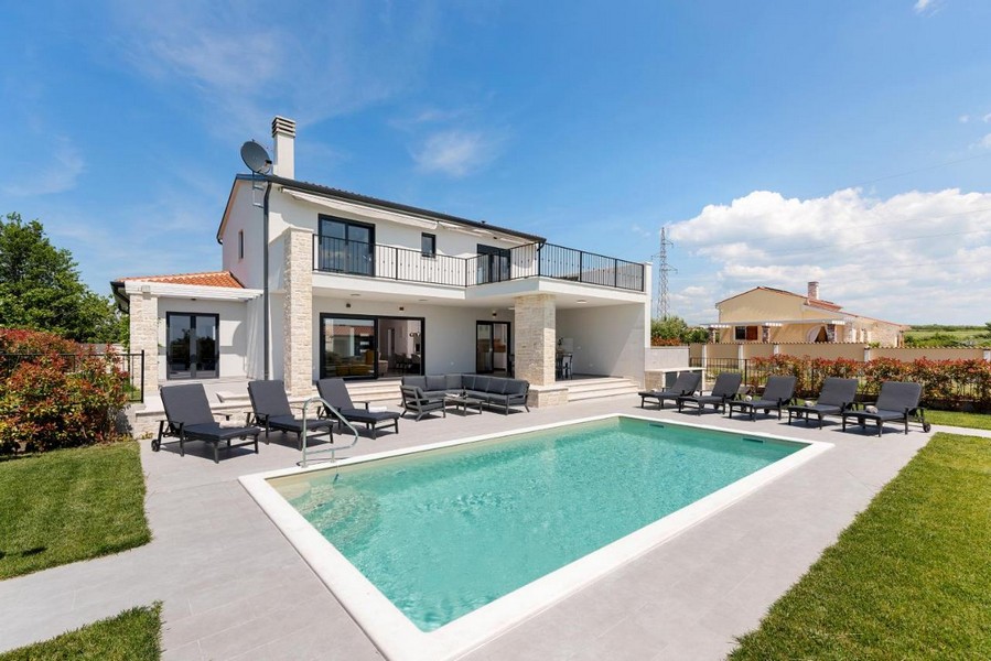 Villa avec soubassement en pierre naturelle et piscine avec rangée de transats