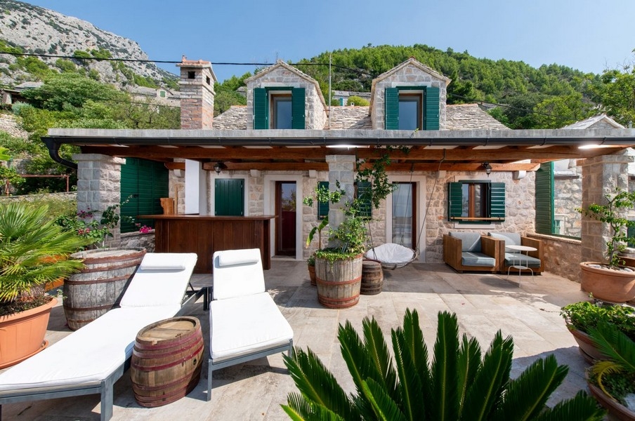 Maison en pierre avec volets verts et transats sous la pergola