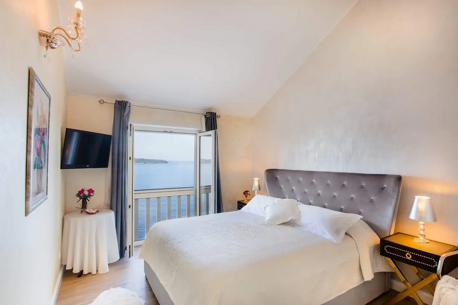 Chambre lumineuse avec lit double et balcon donnant sur la mer