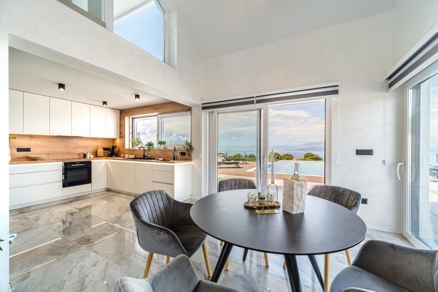 Coin repas avec vue sur la piscine et la mer à travers les fenêtres panoramiques