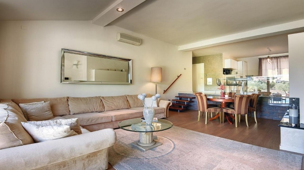 Séjour confortable avec canapé d'angle, miroir et coin repas