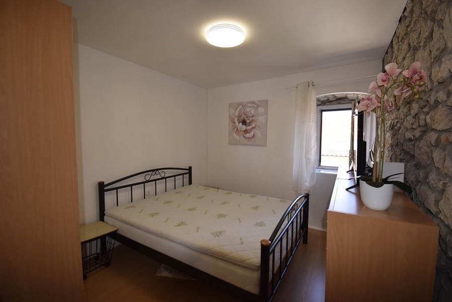 Chambre lumineuse avec lit double et mur en pierre