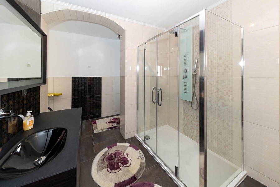 Salle de bains moderne avec grande douche en verre et meuble-lavabo foncé