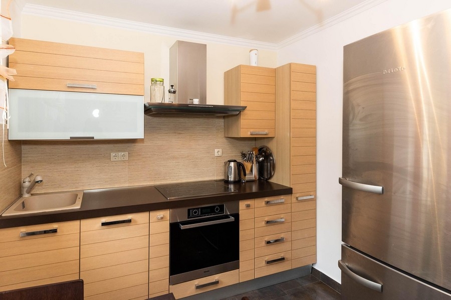 Cuisine équipée moderne avec façades en bois et réfrigérateur en inox