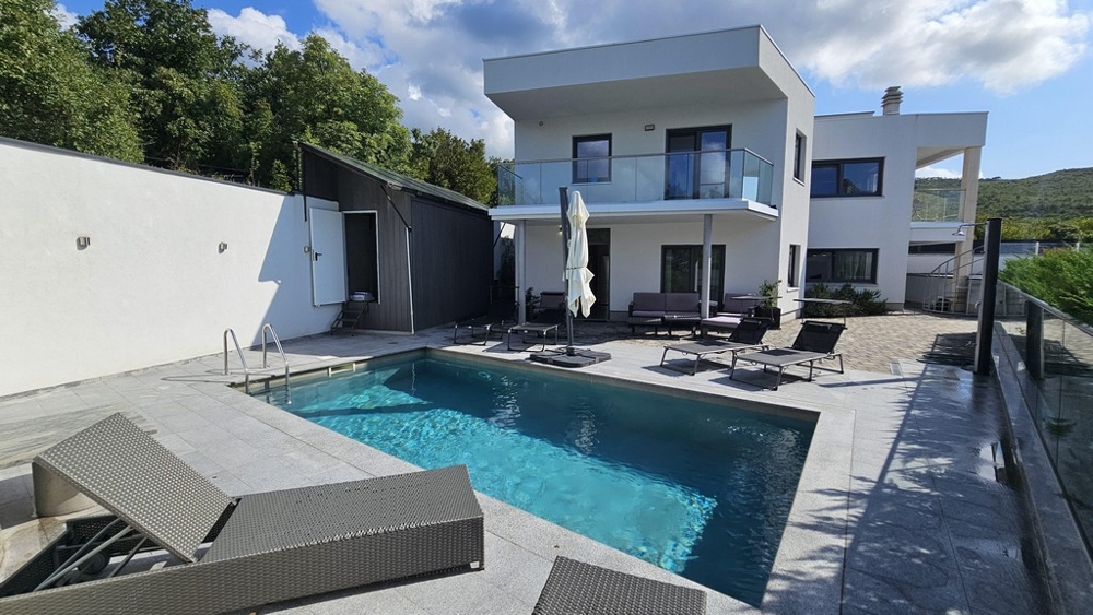 Piscine avec transats devant la villa blanche au balcon en verre