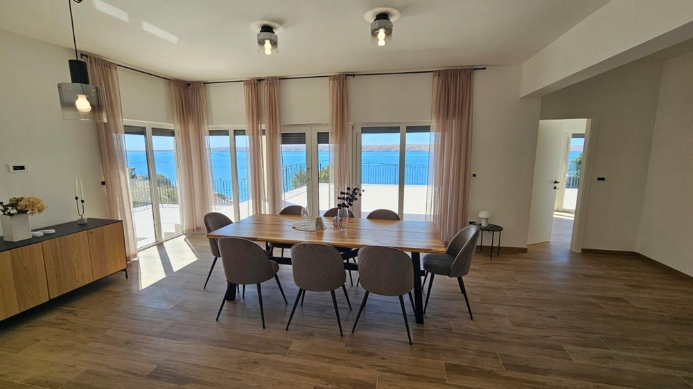 Salle à manger lumineuse avec grande table et vue mer