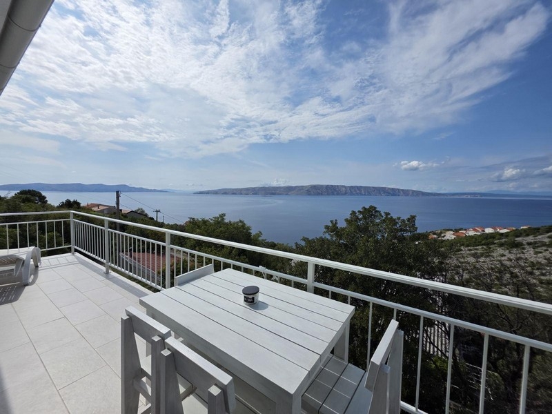 Balcon avec table et vue sur la baie jusqu'à l'île