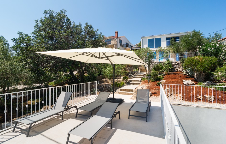 Terrasse avec bains de soleil et parasol devant une maison méditerranéenne