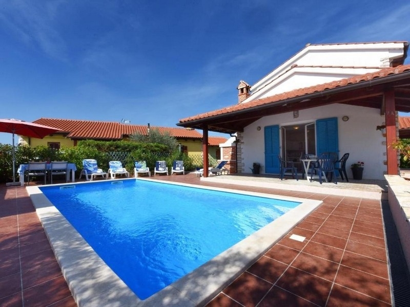 Piscine avec volets bleus sur la maison et parasol