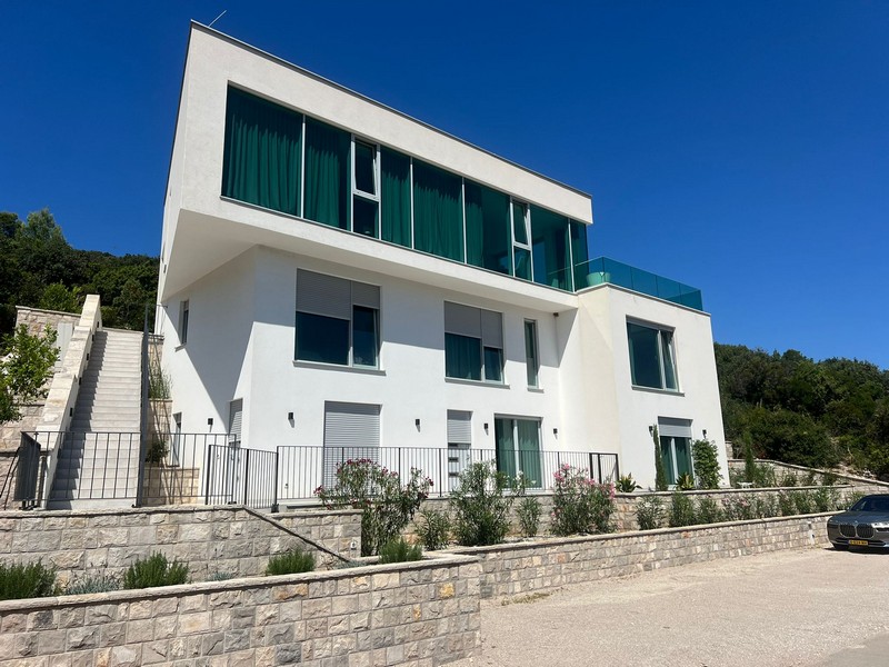Maison blanche avec garde-corps en verre vert au-dessus du mur en pierres sèches