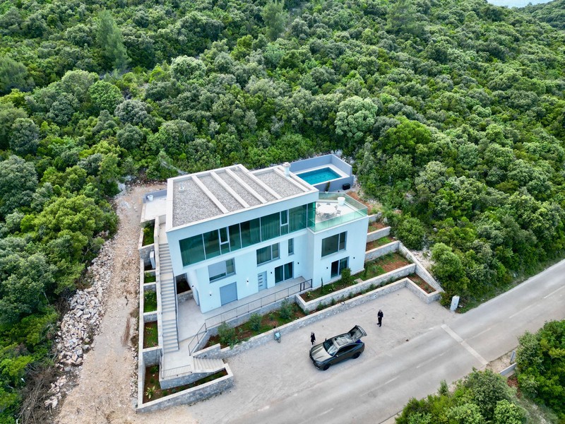 Vue aérienne de la villa avec piscine sur le toit entre des versants boisés