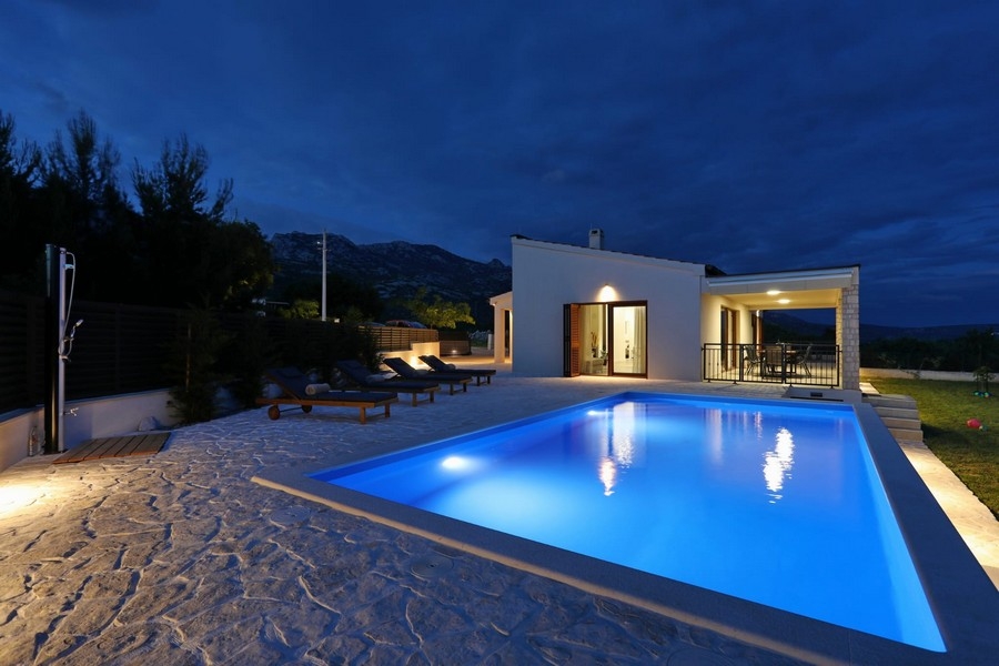 Piscine éclairée devant la maison à l'heure bleue
