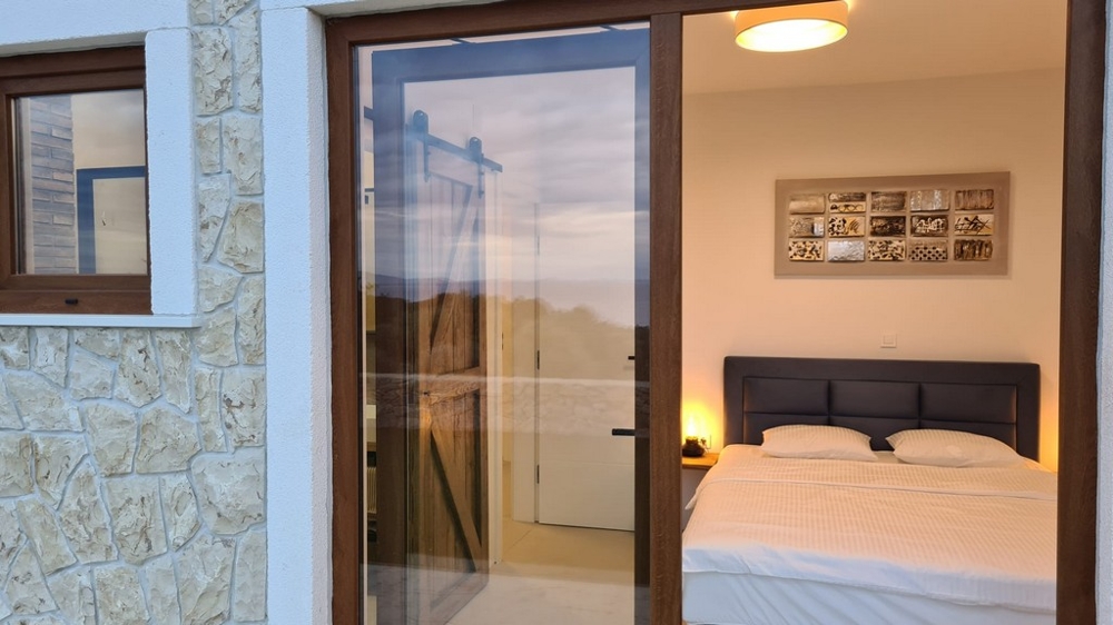 Vue par la porte coulissante sur la chambre avec lit en bois