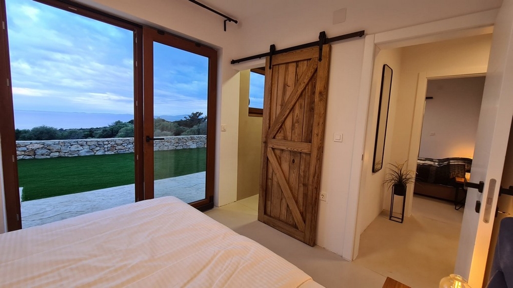 Chambre avec porte coulissante en bois et vue sur la pelouse