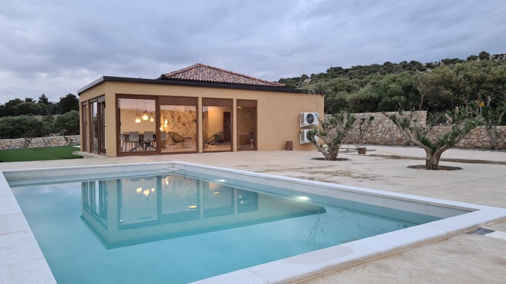 Piscine devant la maison avec grande façade vitrée le soir