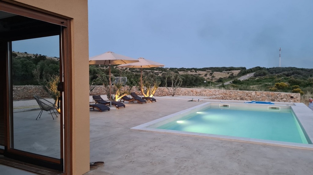 Vue de la pièce sur la piscine et les parasols
