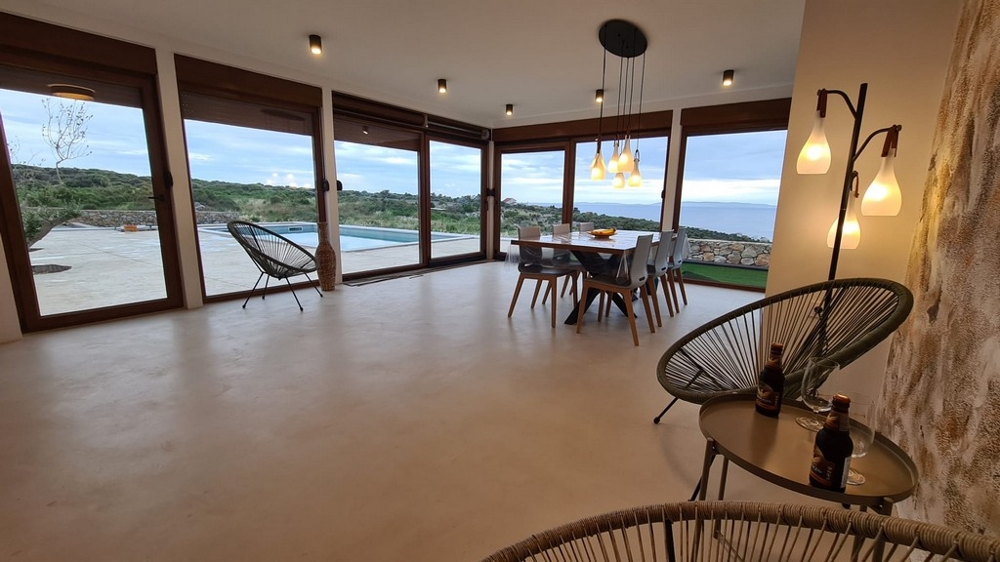 Séjour avec façade vitrée donnant sur la piscine et fauteuils en fil métallique