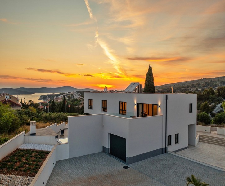 Villa blanche avec cyprès au coucher du soleil au-dessus de la baie