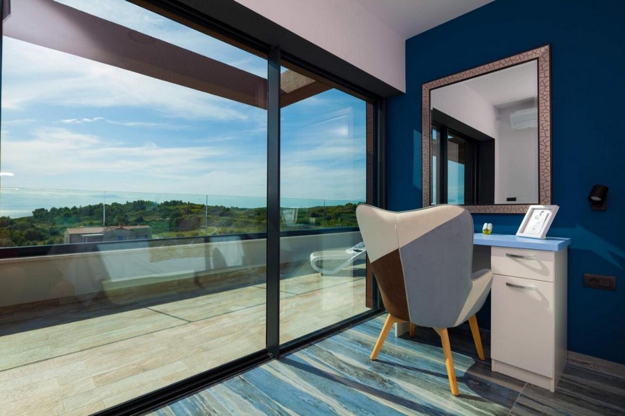 Chambre avec coiffeuse et grande baie vitrée donnant sur la terrasse