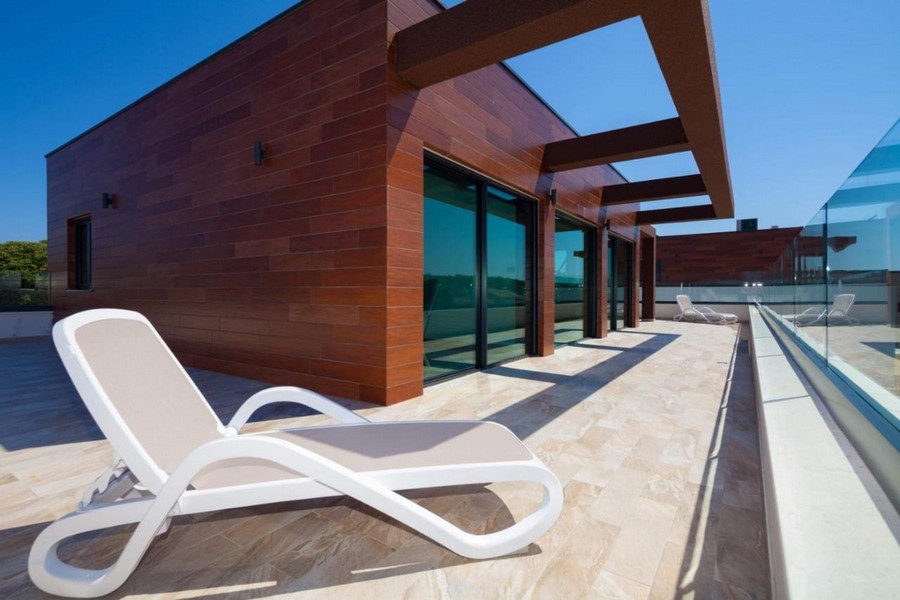 Toit-terrasse avec transat devant la façade en bois et la pergola
