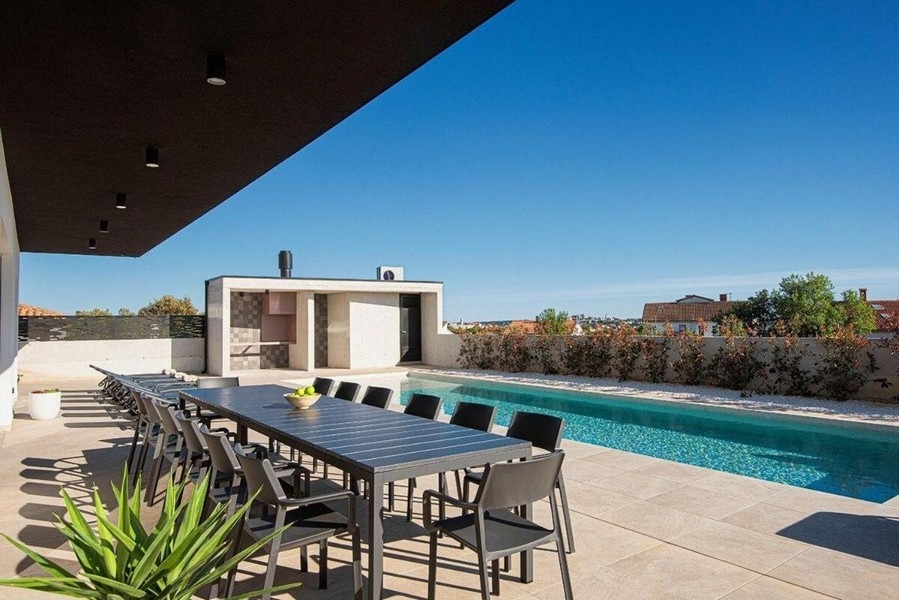Terrasse avec grande table à manger et vue sur la piscine