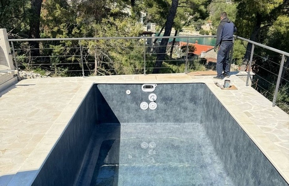 Piscine en construction avec ouvrier sur la terrasse
