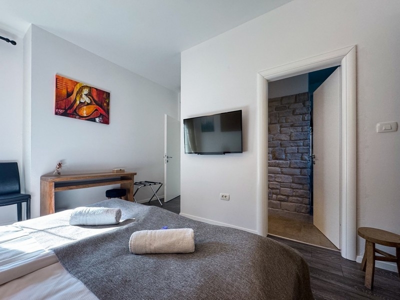 Chambre lumineuse avec TV et détails en pierre murale