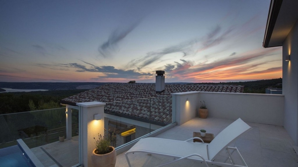Terrasse de la villa avec bains de soleil et vue panoramique au coucher du soleil