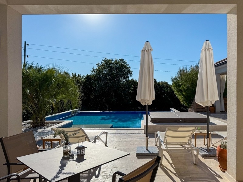 Terrasse couverte avec coin salon et vue sur la piscine
