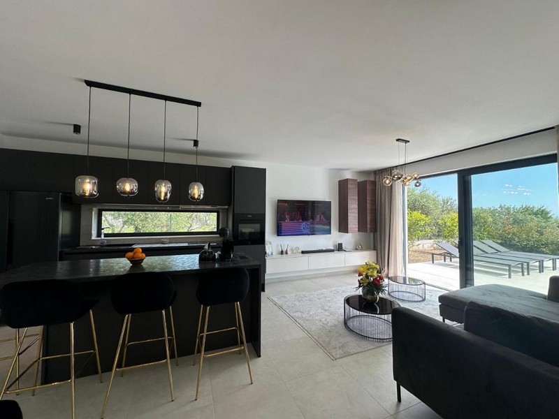 Cuisine moderne avec coin repas et vue sur la terrasse.