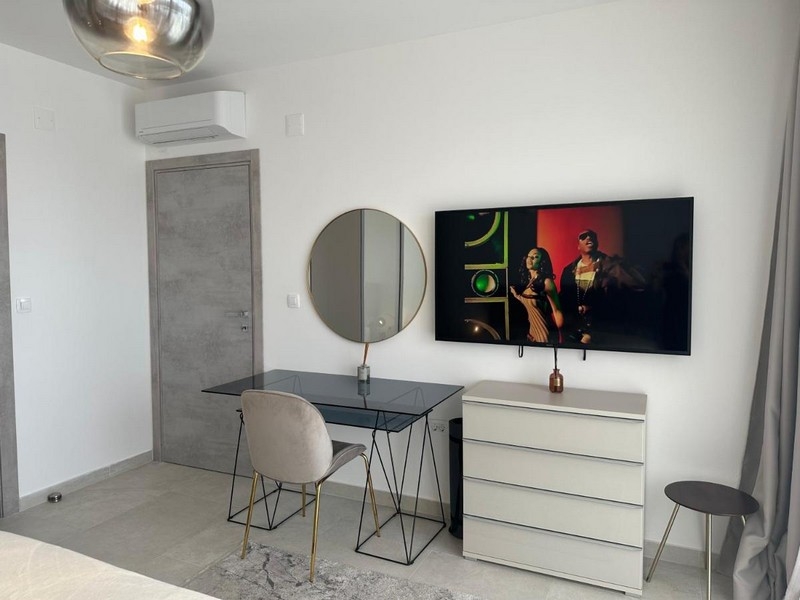 Chambre au mobilier moderne avec bureau, miroir et télévision