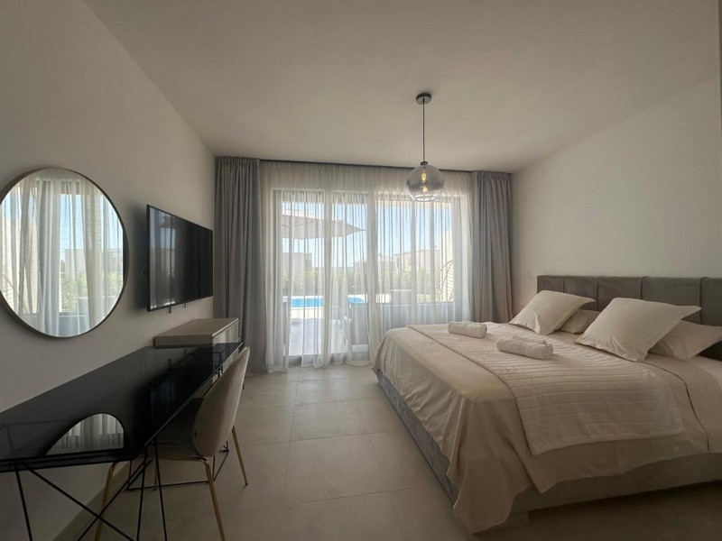 Chambre avec lit double et vue sur la terrasse avec piscine