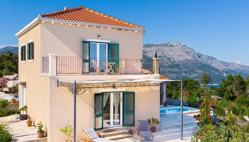 Maison avec volets verts et balcon devant la chaîne de montagnes