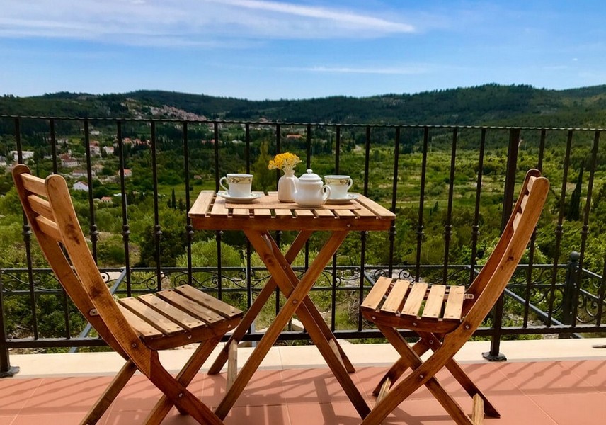 Balcon avec table et chaises, vue sur les collines