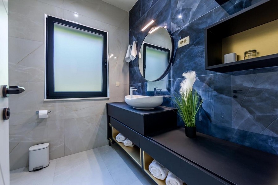 Salle de bains avec mur en marbre bleu et miroir rond