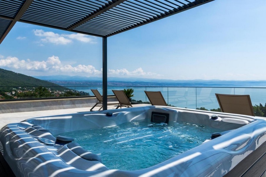 Jacuzzi sous la pergola à lames avec vaste vue mer