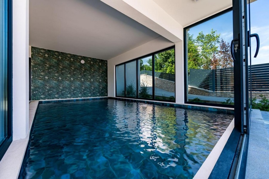 Piscine intérieure avec grande façade vitrée et vue sur le jardin