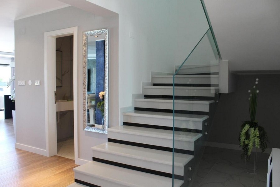 Escalier avec garde-corps en verre et couloir lumineux
