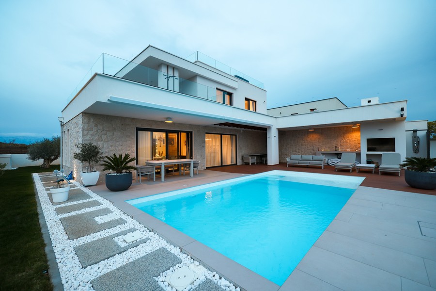 Villa éclairée avec piscine et bande de gravier au crépuscule