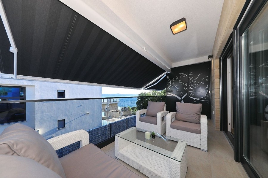 Terrasse couverte avec salon de jardin et vue partielle sur la mer