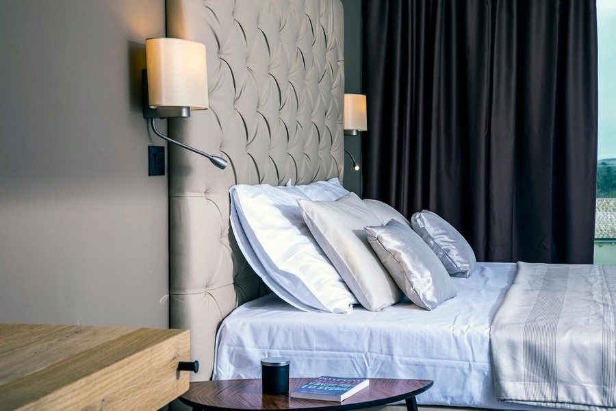Chambre beige avec tête de lit capitonnée.
