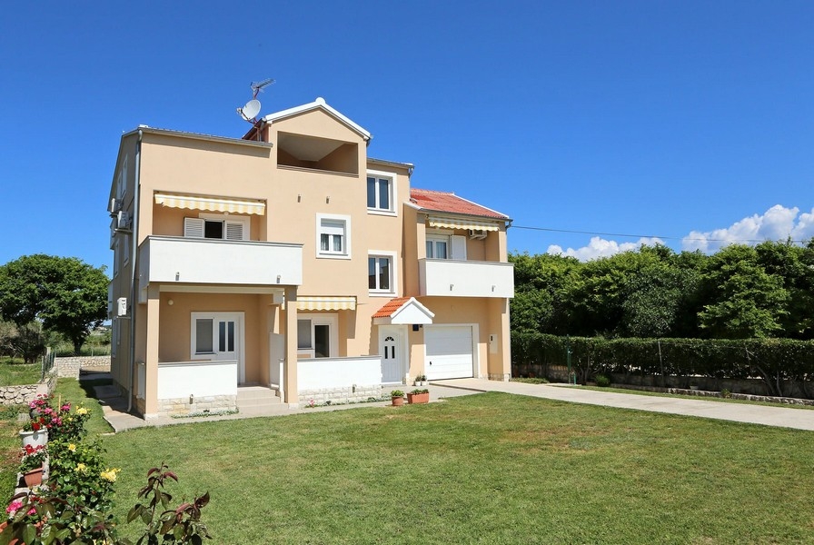 Maison abricot avec stores et garage sur la pelouse