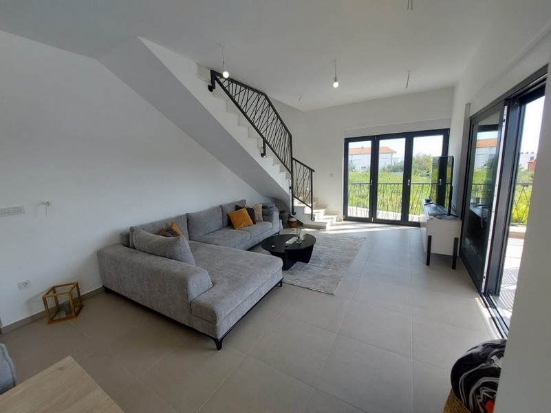 Séjour lumineux avec canapé et escalier