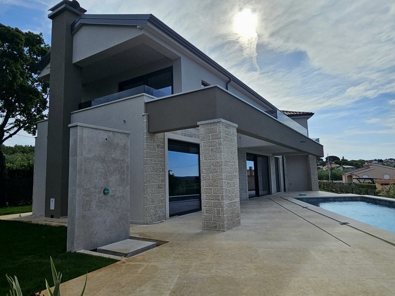 Maison avec colonnes en pierre naturelle et piscine à contre-jour