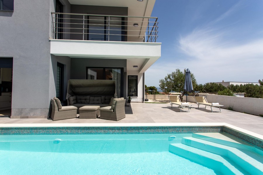 Terrasse de la piscine avec coin salon sous le balcon de la villa