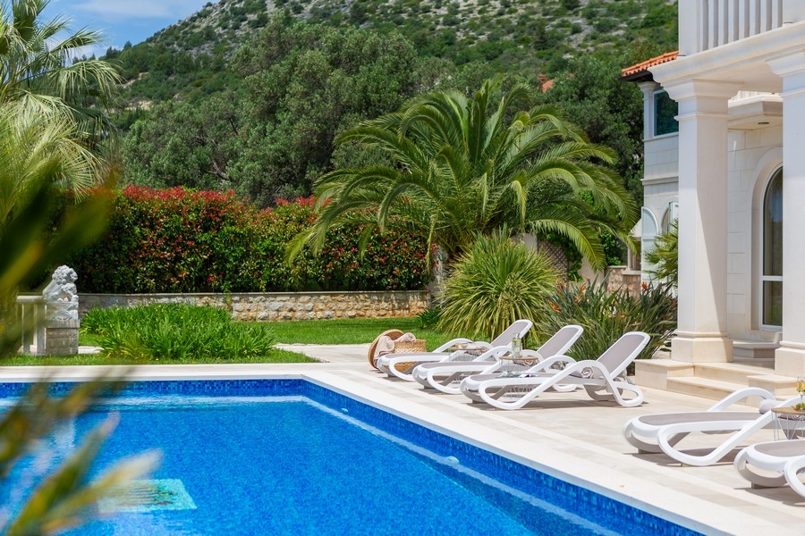 Espace piscine avec chaises longues et jardin